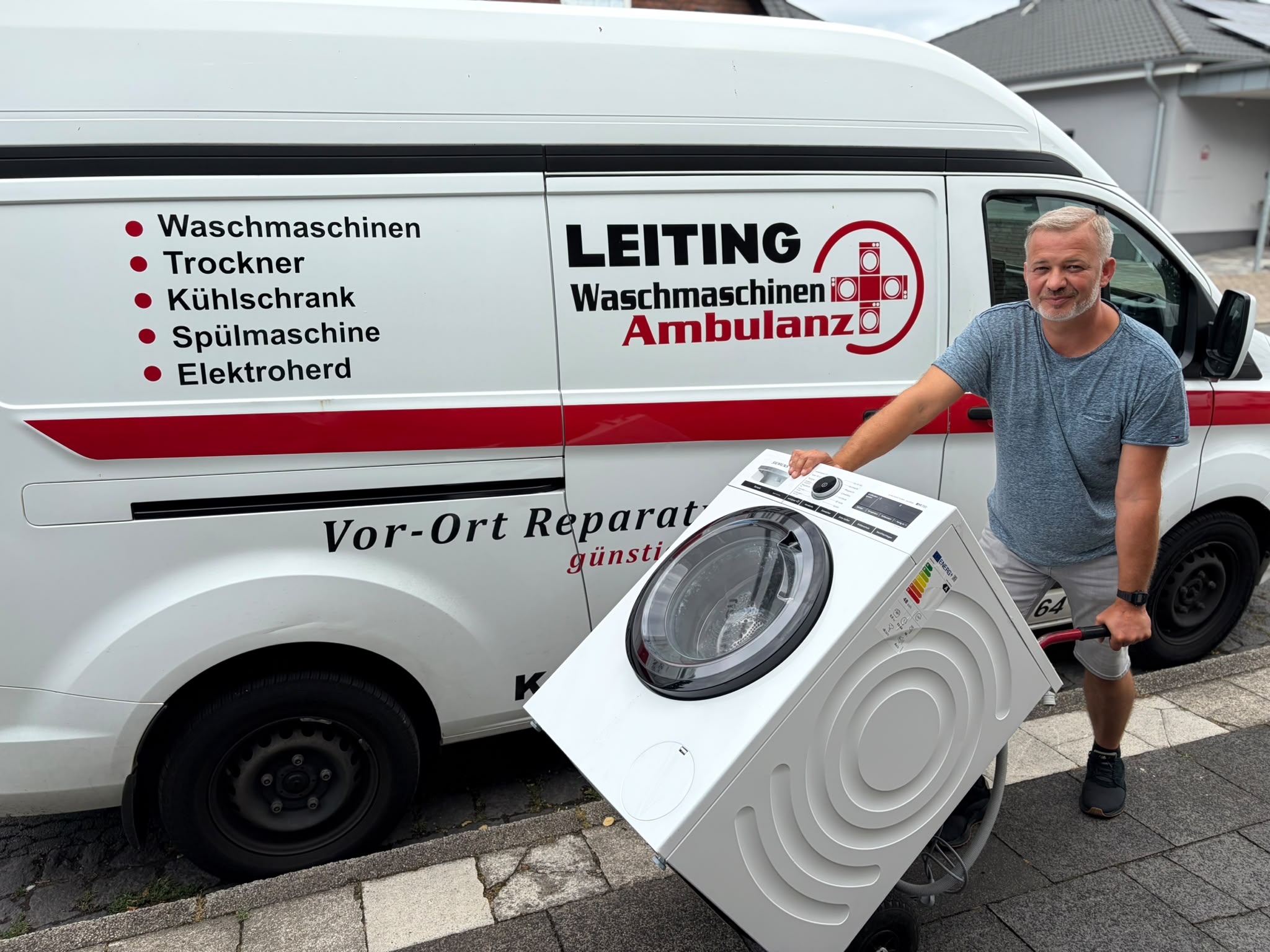 Techniker der Waschmaschinen-Ambulanz mit Waschmaschine am Servicefahrzeug